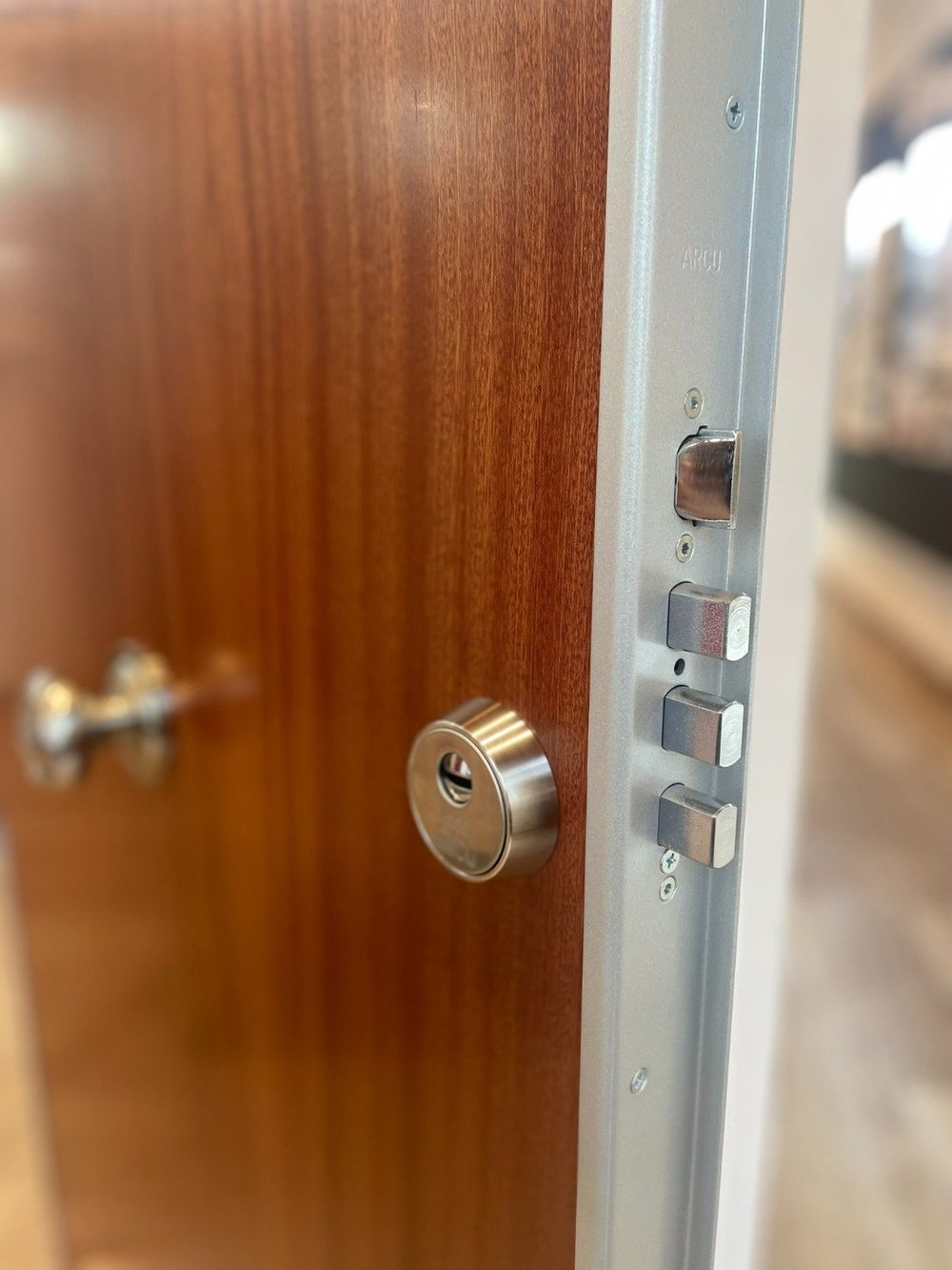 Cerradura de seguridad en una puerta de madera parcialmente abierta en un marco metálico.